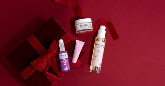 Lavera Pflegeprodukte mit roter Geschenkbox auf dunkelrotem Hintergrund