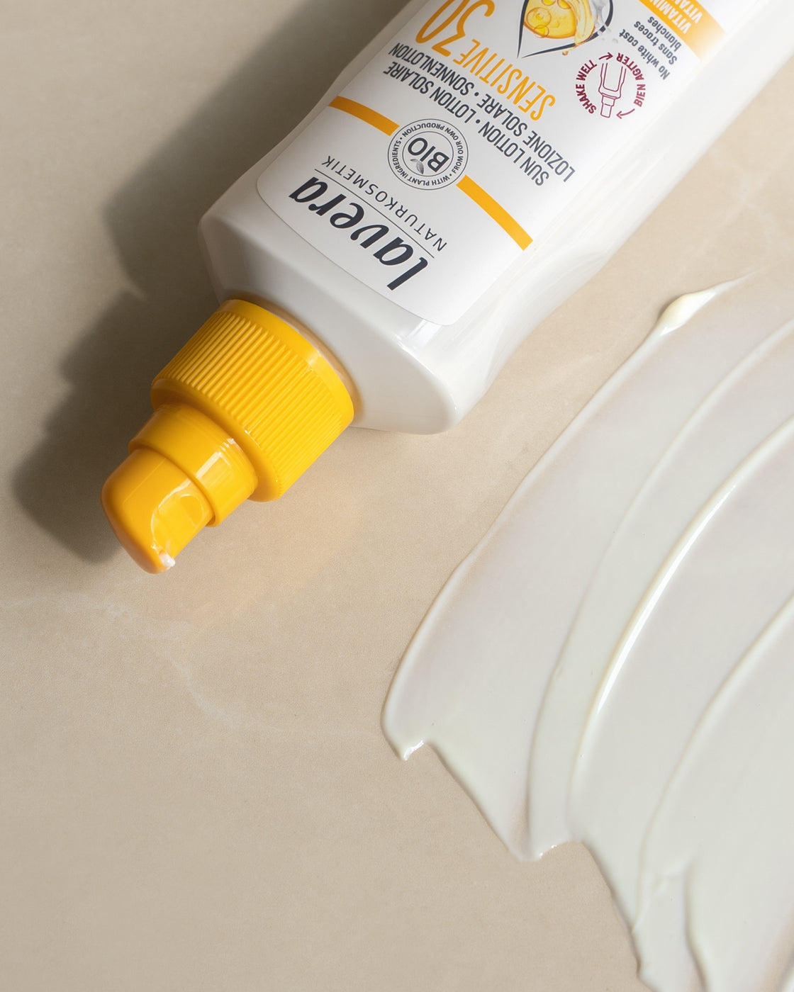 lavera Sensitiv Sonnenlotion LSF 30 mit gelber Kappe und Produkttextur