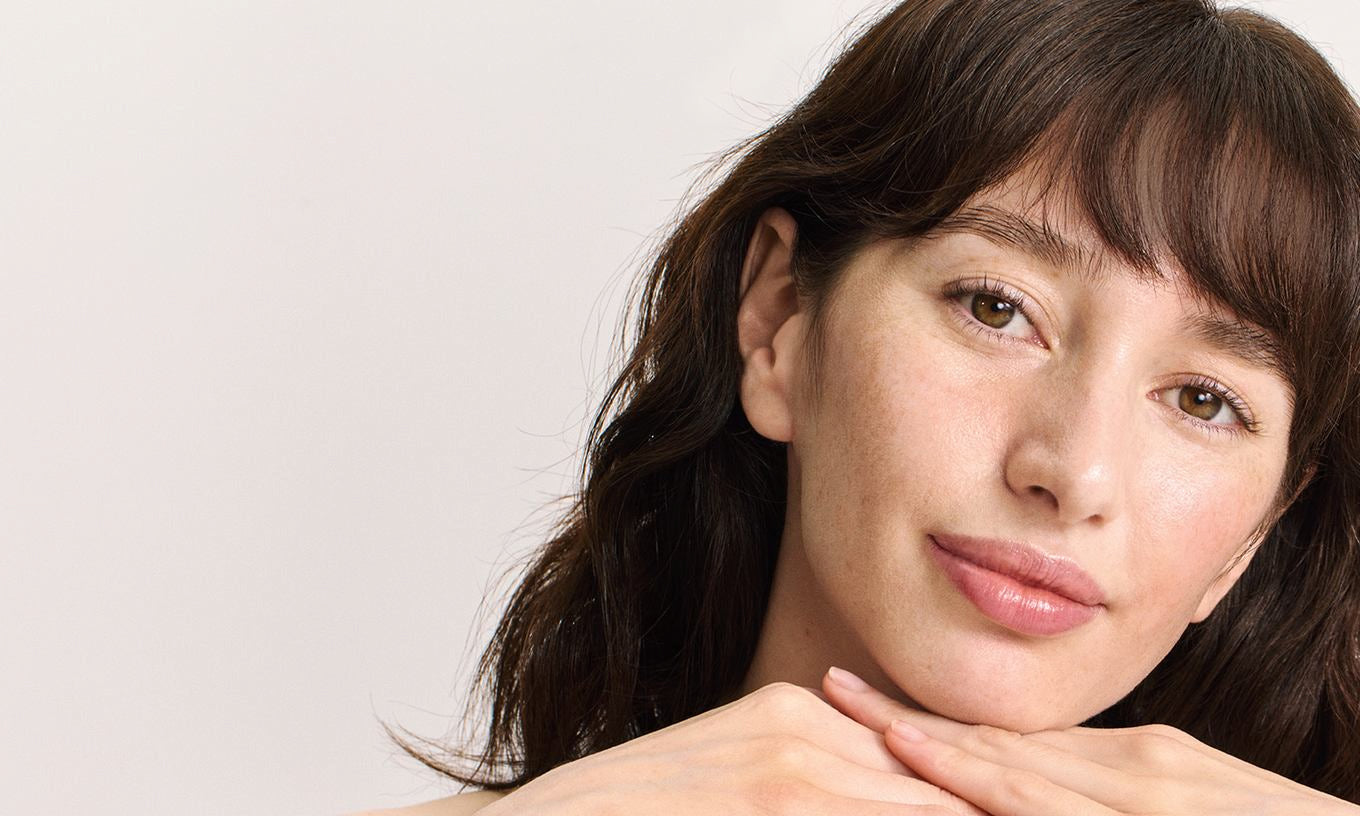 Porträt einer Frau mit dunklem Pony, Kinn auf Händen, natürlicher Look