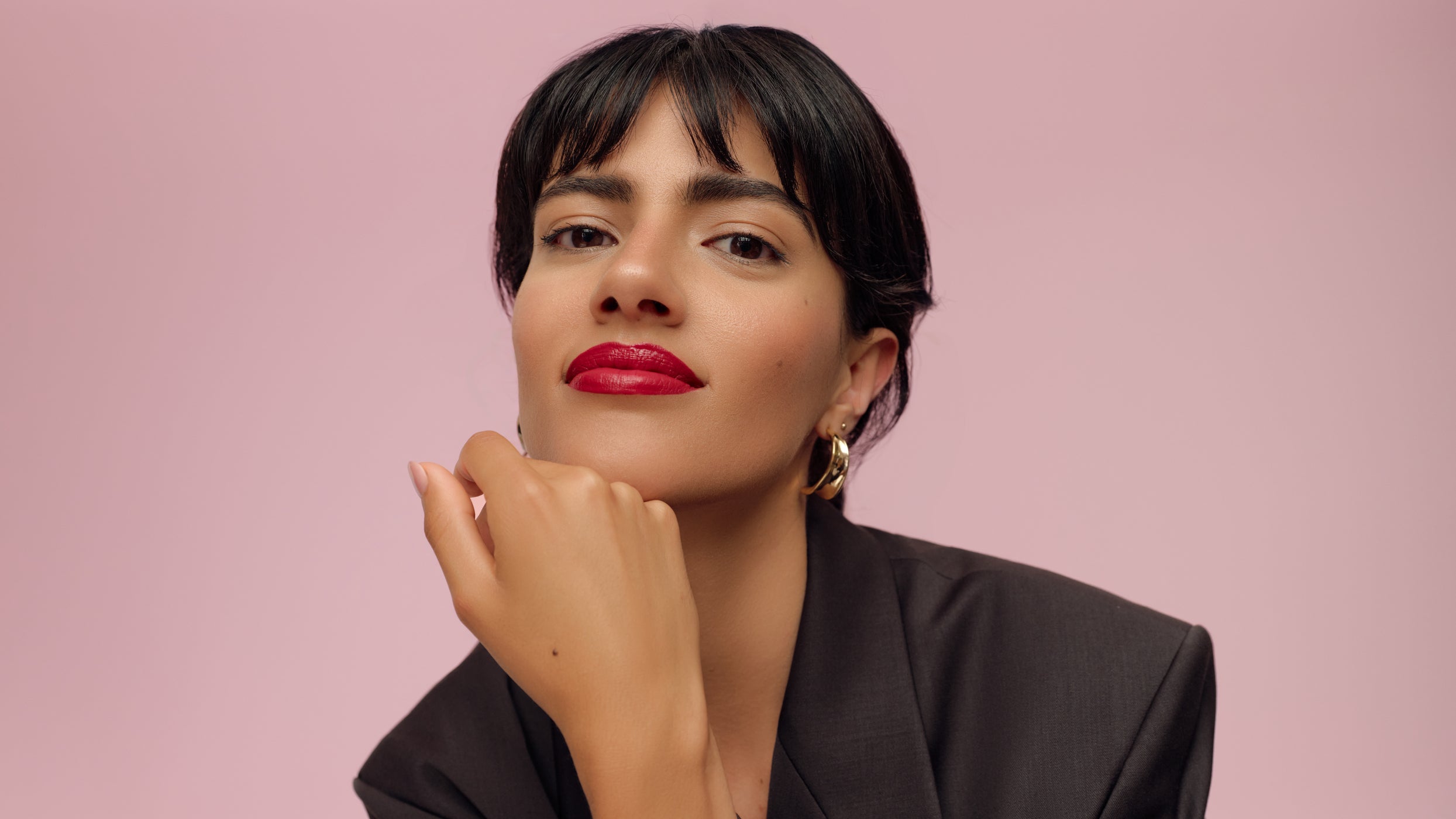 Porträt: Frau mit rotem Lippenstift vor rosa Hintergrund, eleganter Look