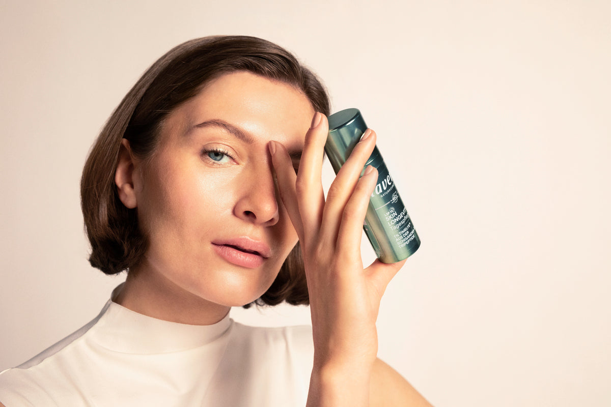 Frau mit braunen, schulterlangen Haaren hält Skin Longevity Tagespflege