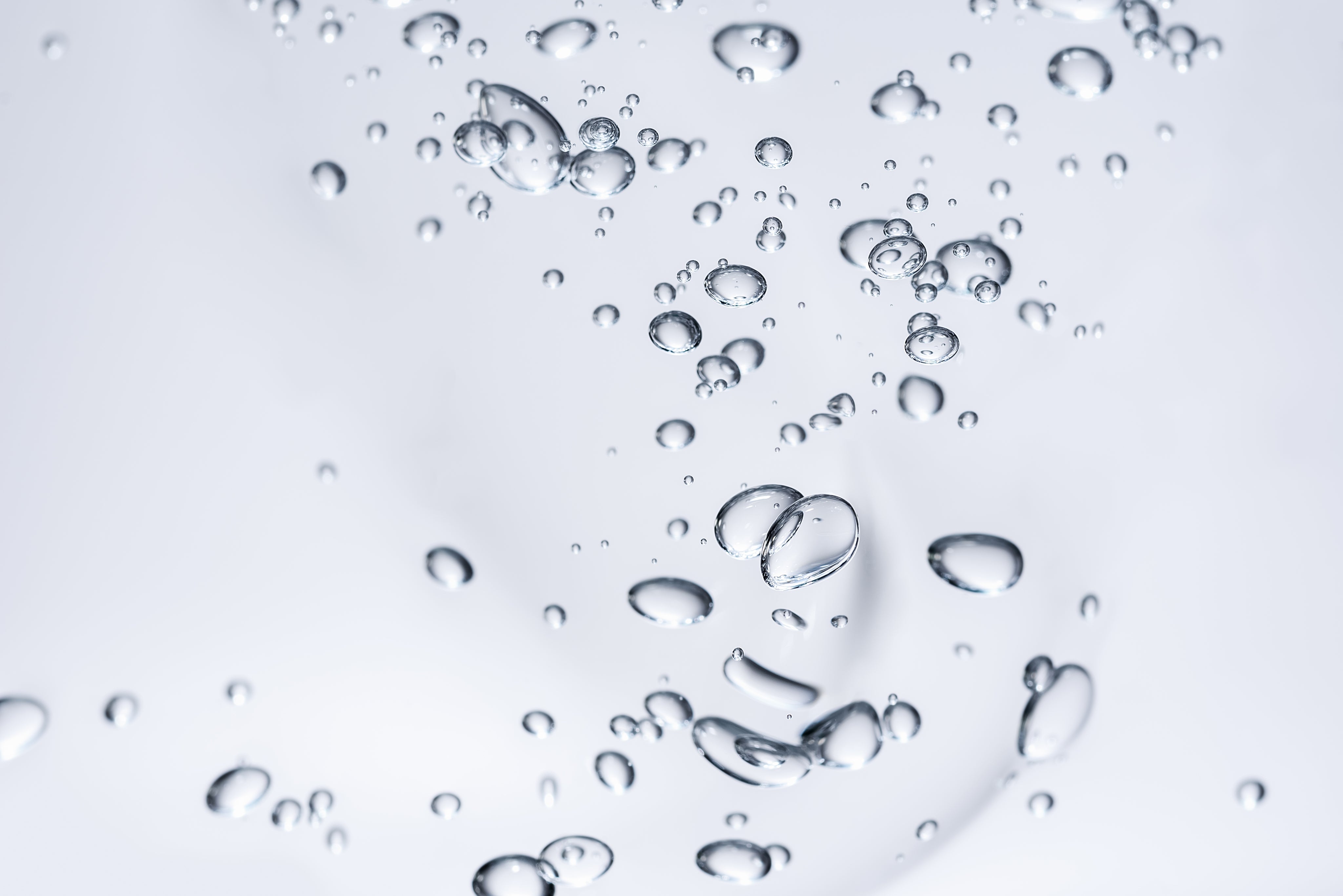 Schwebende Wassertröpfchen auf hellem Hintergrund, frische Hydration