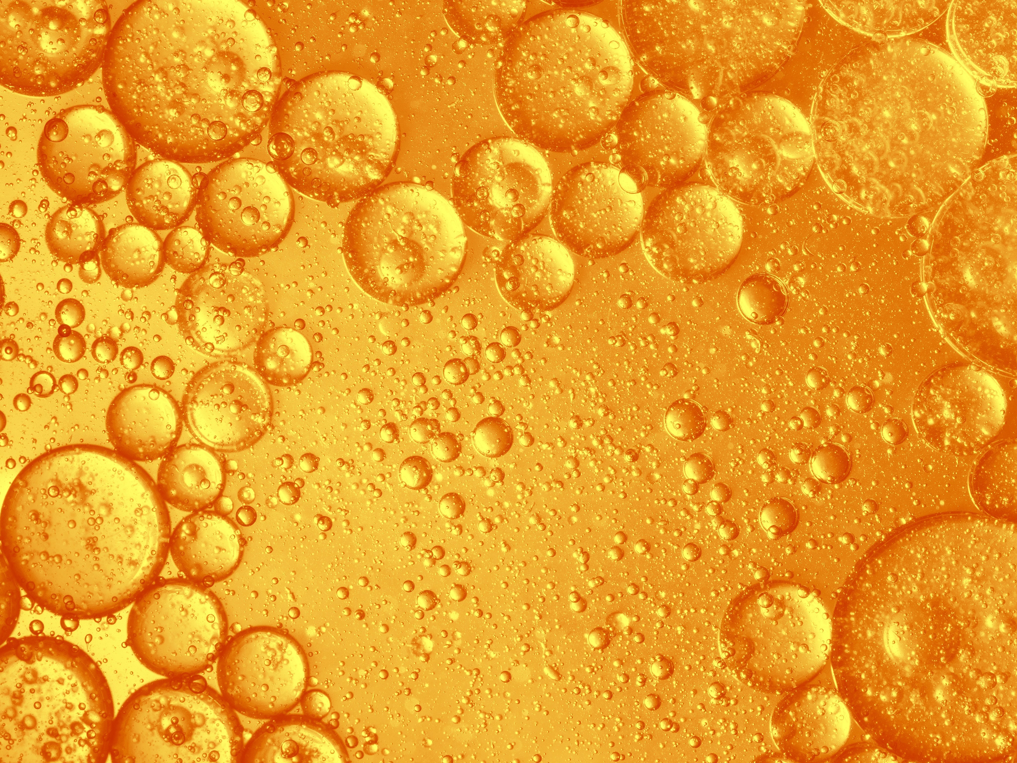 Makro: orangefarbene Öltröpfchen und Bläschen in Flüssigkeit