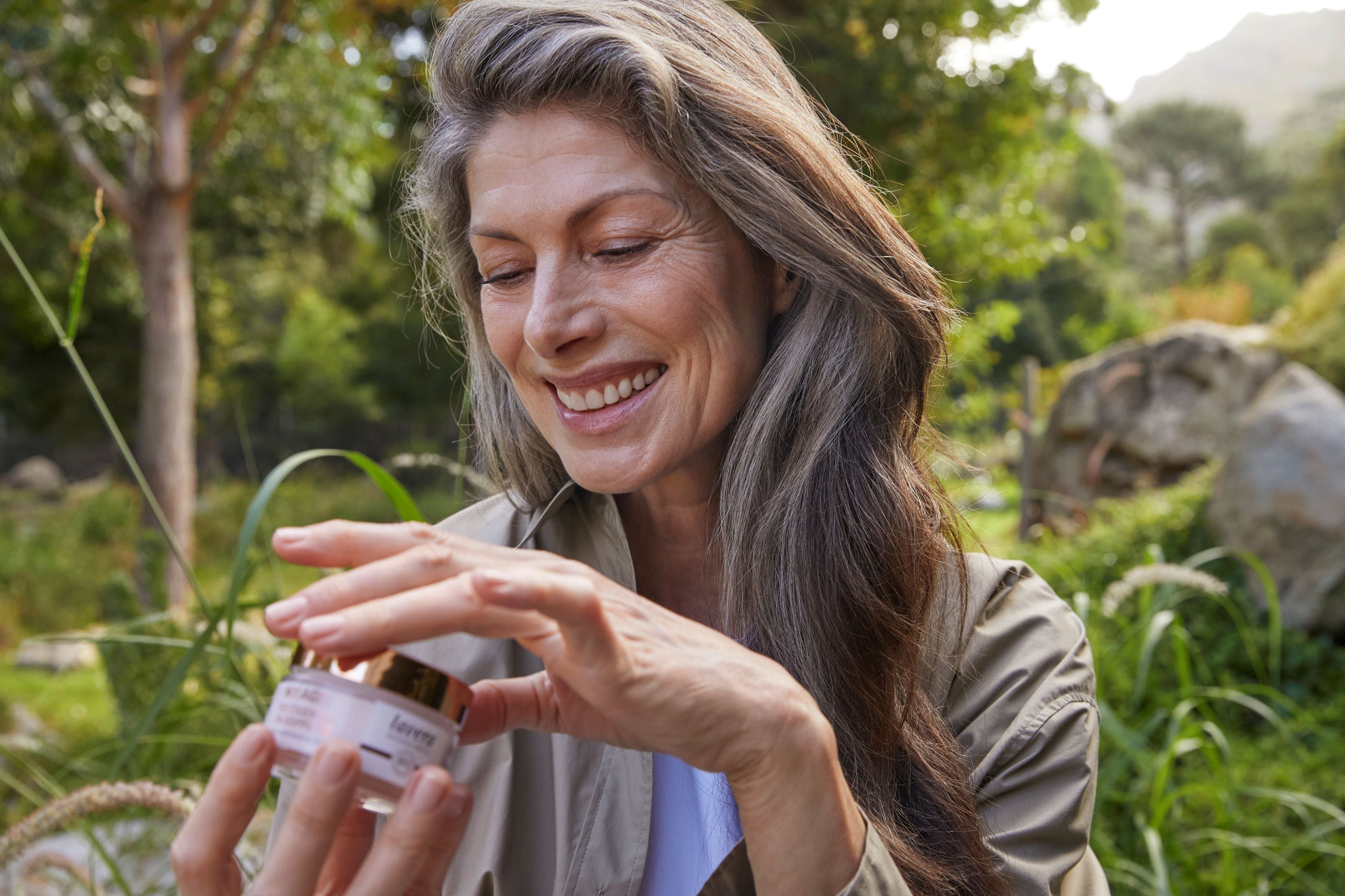Frau in der Natur hält die lavera My Age Creme in den Händen