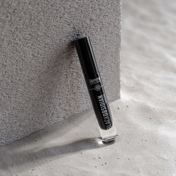 Lavera Black Obsidian Mascara lehnt an einem grauen Stein