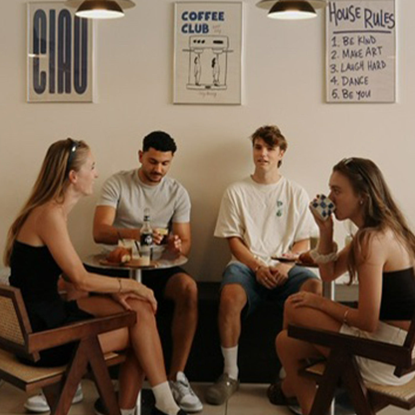 Gruppe aus zwei jungen Männern und zwei Frauen sitzt zusammen