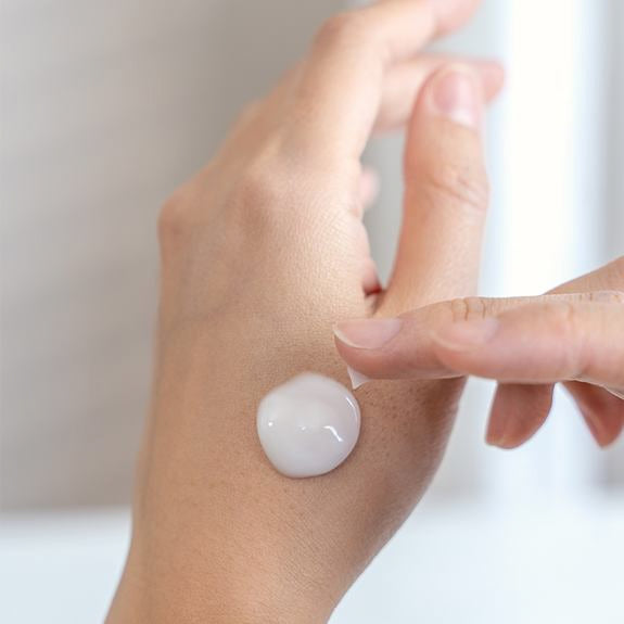 Creme wird als Tropfen auf den Handrücken aufgetragen