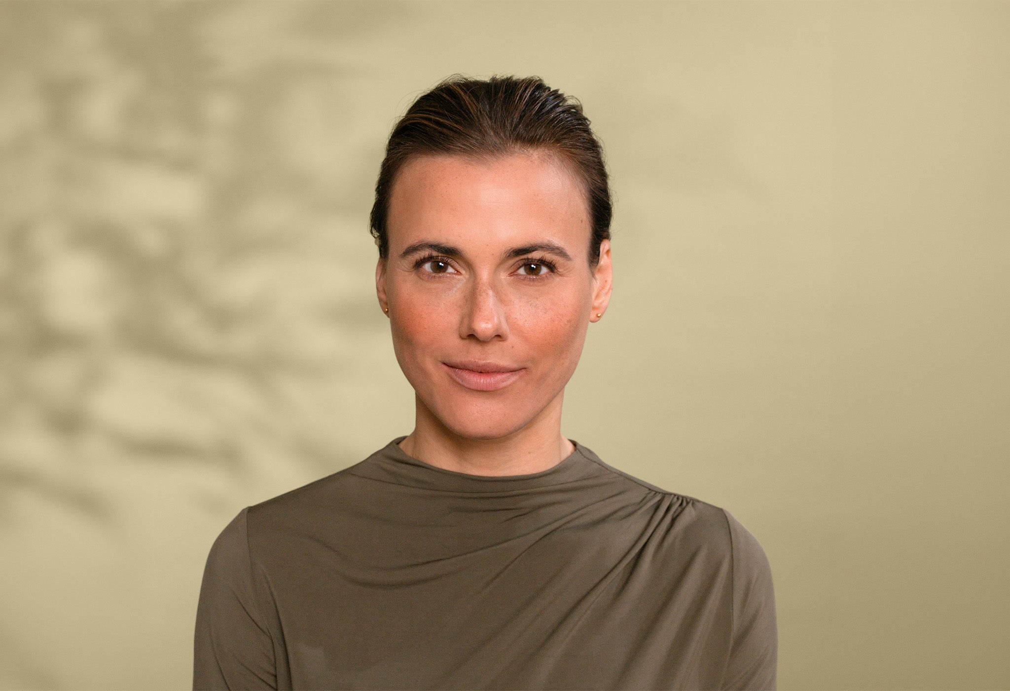 Portrait einer Frau mit braunen Augen und braunen Haaren vor grünem Hintergrund