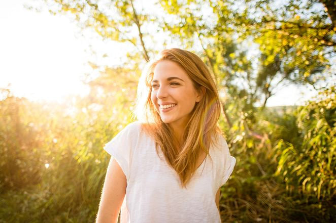 Frau im Feld im warmen Sonnenlicht lächelnd