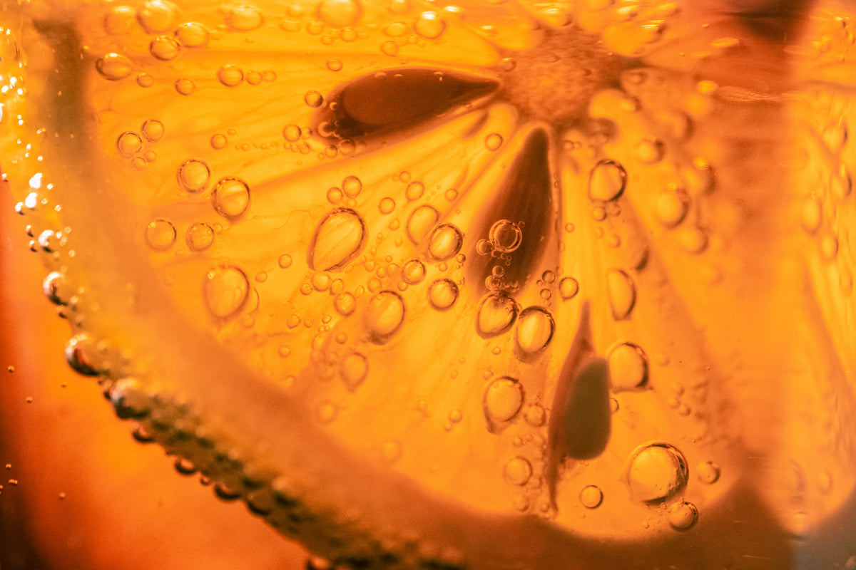 Nahaufnahme einer Orange mit Fruchtfleisch und Wassertropfen als Symbol für den Inhaltsstoff Vitamin C