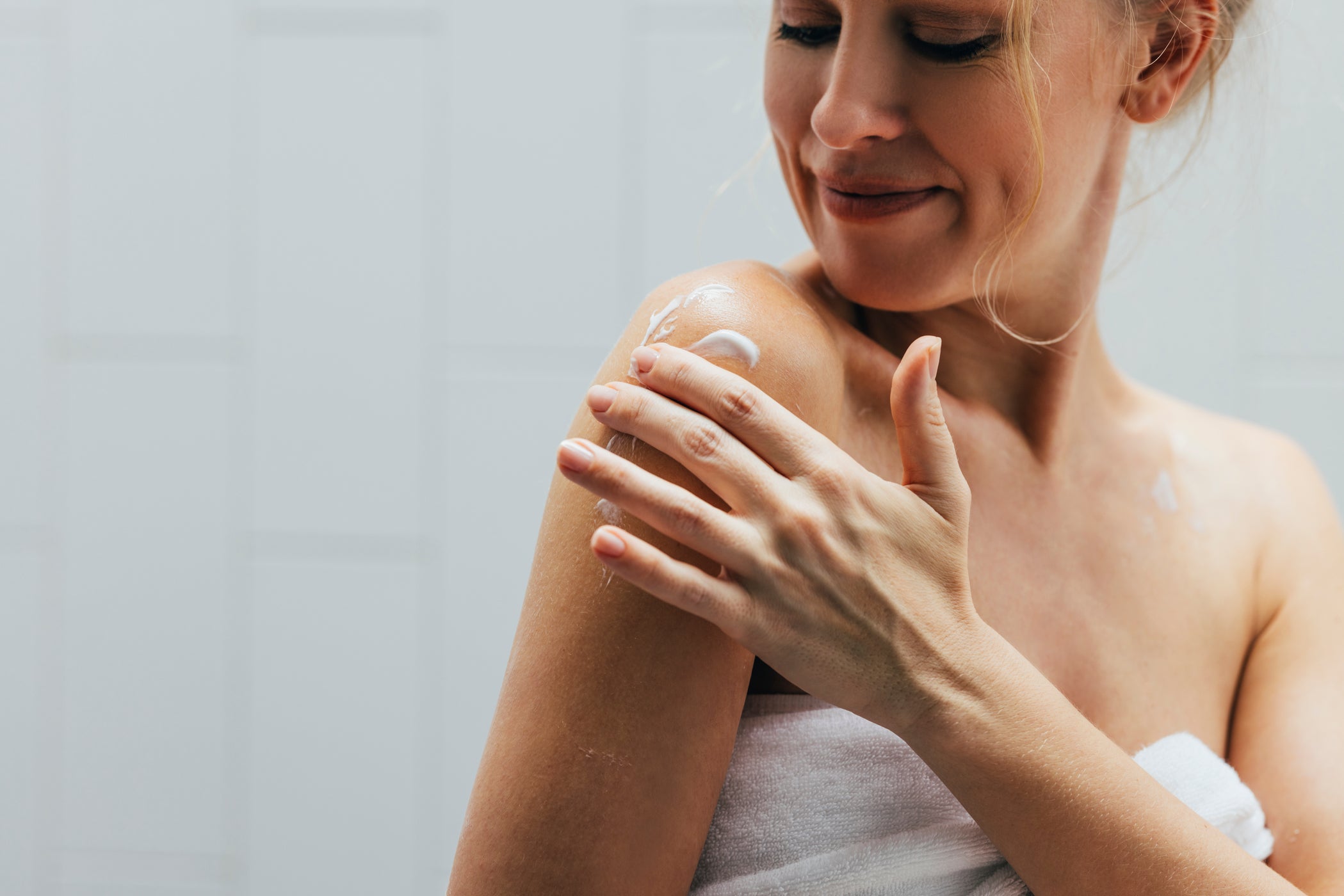 Nahaufnahme des Oberarms einer weiblichen Person, die sich eincremt