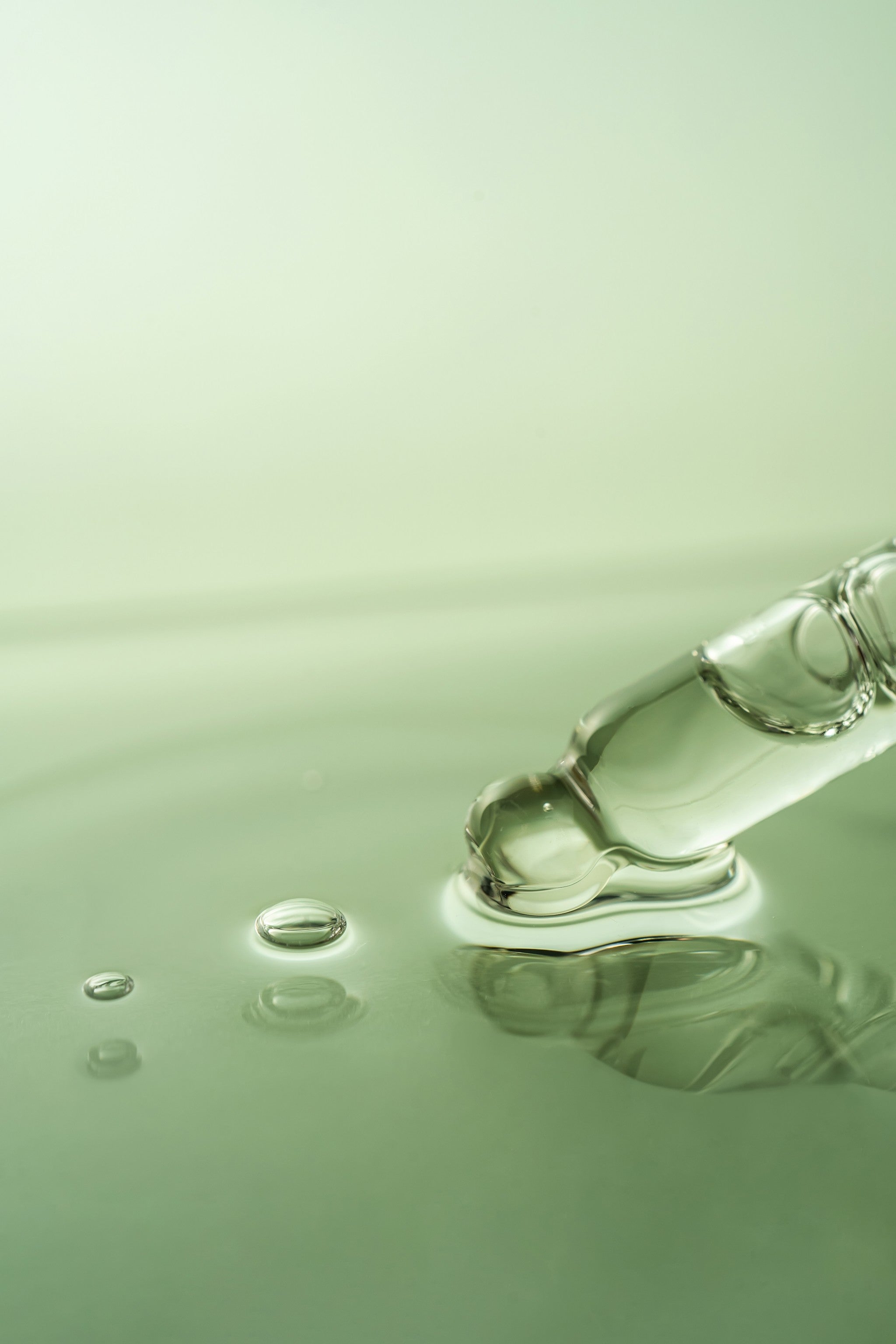 Nahaufnahme einer Pipette mit klarer Flüssigkeit, die Tropfen in Wasser abgibt.