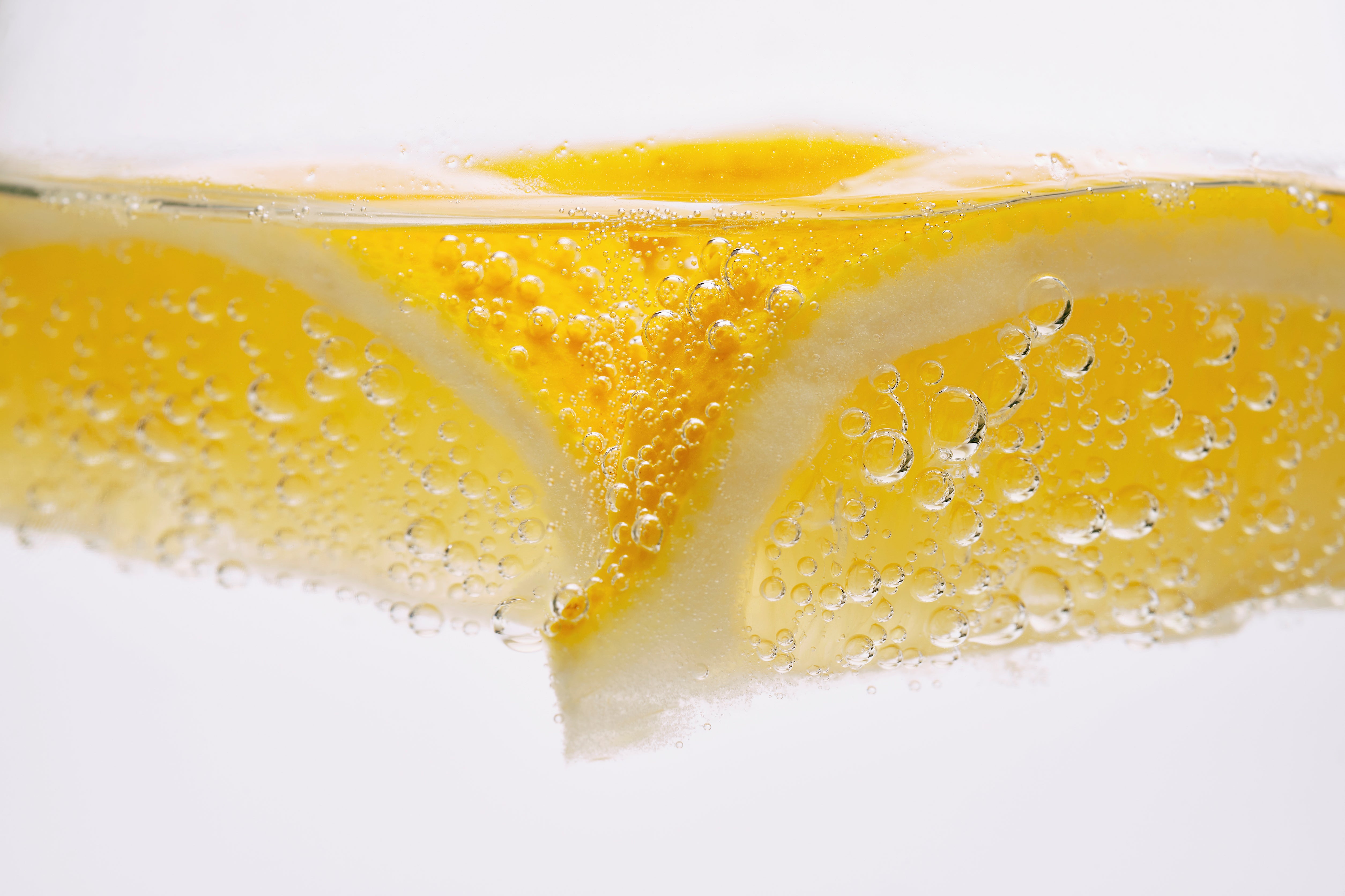 Zwei Zitronenstücke in Wasser mit Luftblasen