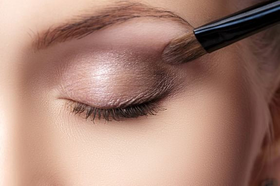 Dunkler Lidschatten wird mit Pinsel am äußeren Augenwinkel verblendet