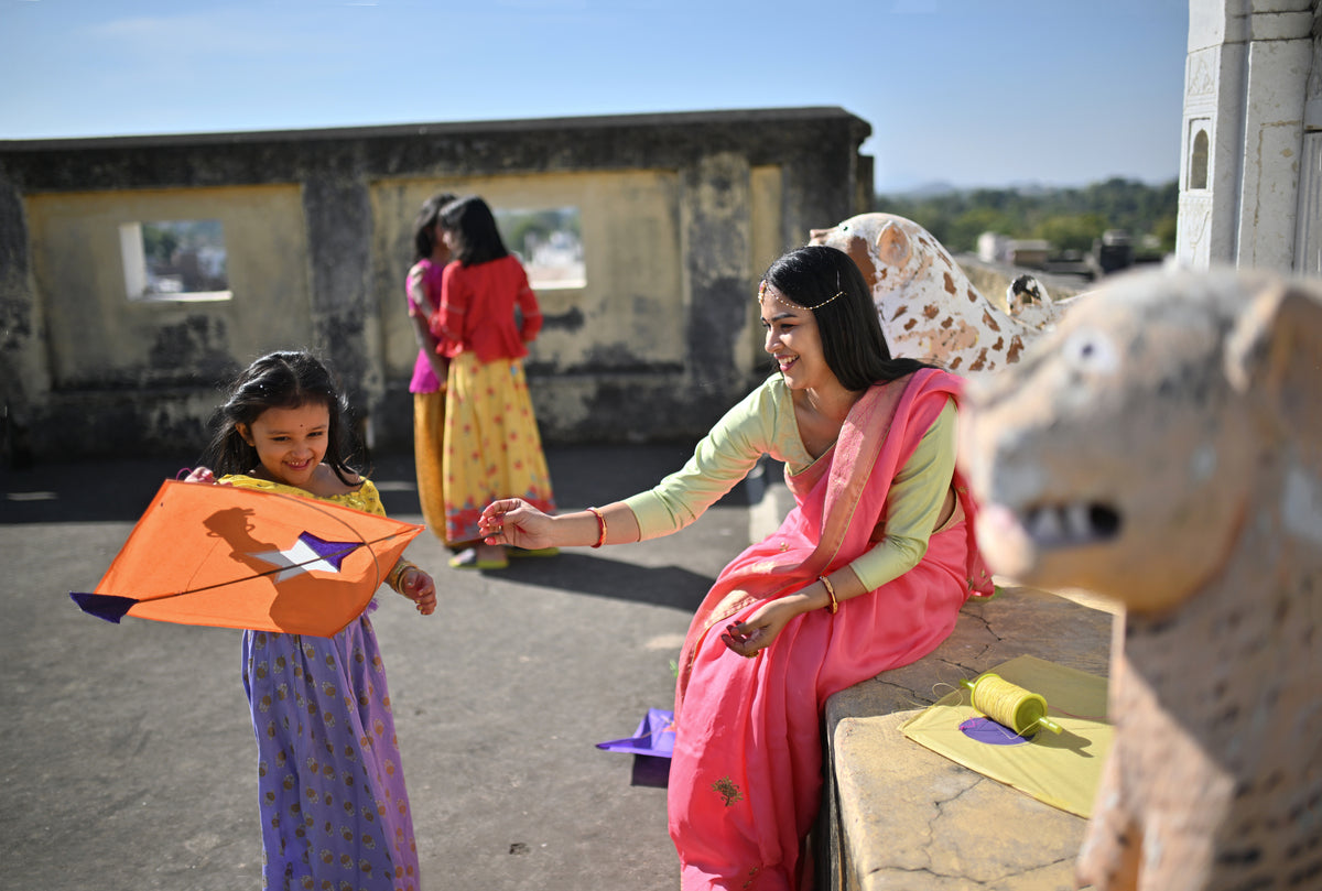 Indische Mutter und Kind in einem Hof mit einem orangenen Drachen