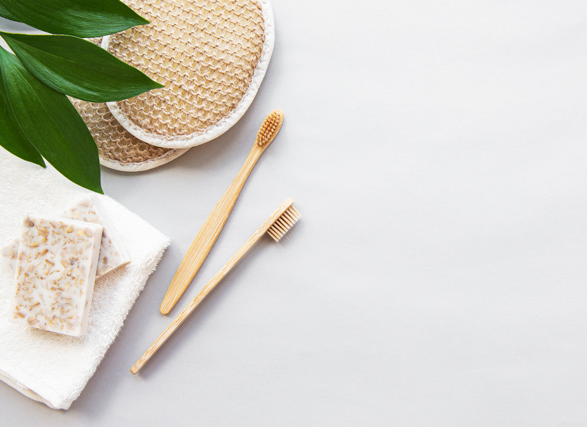 Pflegeutensilien wie Schwann, Zahnbürste und Seite nebeneinander vor weißem Hintergrund