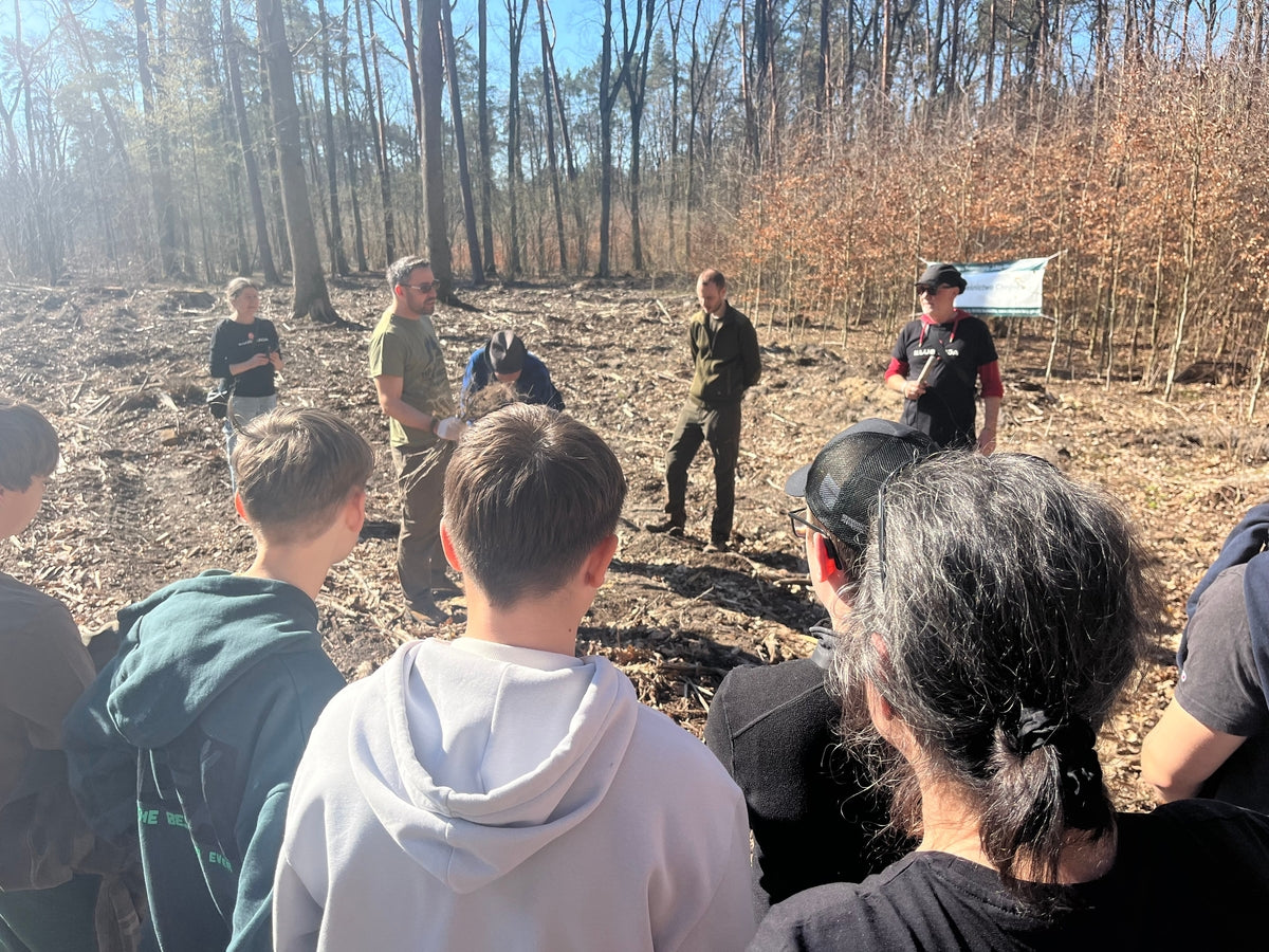 Menschengruppe aus Männern und Frauen steht im Halbkreis im Wald