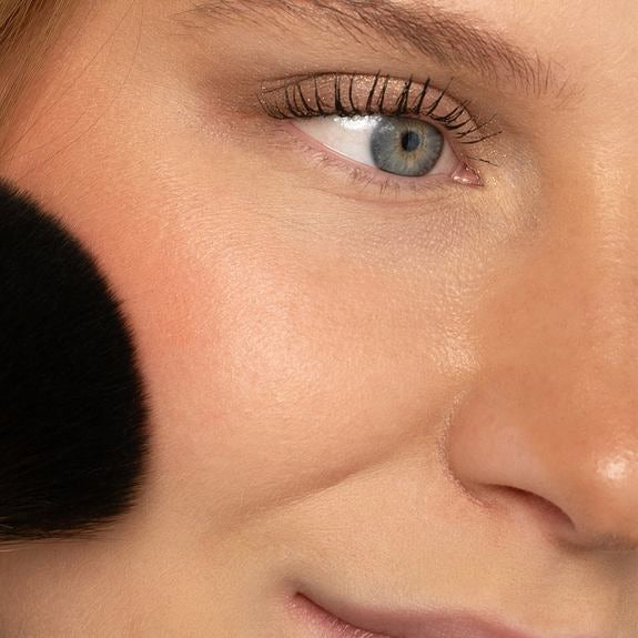 Auftragen von Puderrouge auf die Wange mit Pinsel