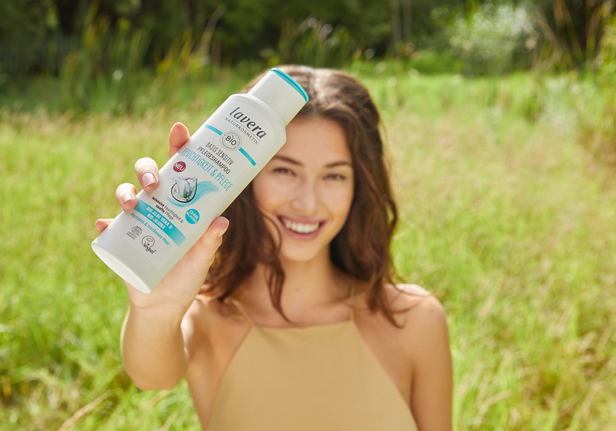 Frau hält Shampoo in die Kamera