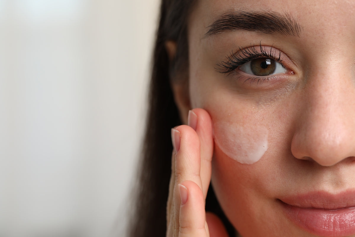 Gesichtshälfte einer jungen Frau mit Creme auf der Wange