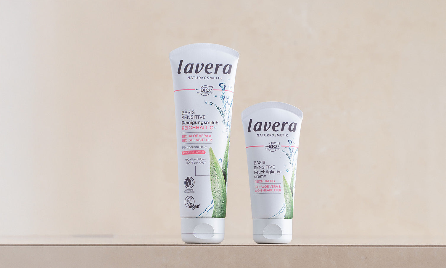basis sensitive Reinigungsmilch und Feuchtigkeitscreme nebeneinander vor beschem Hintergrund