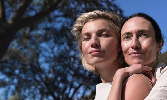 Zwei Frauen im Freien mit natürlichem Look, eng aneinander gelehnt