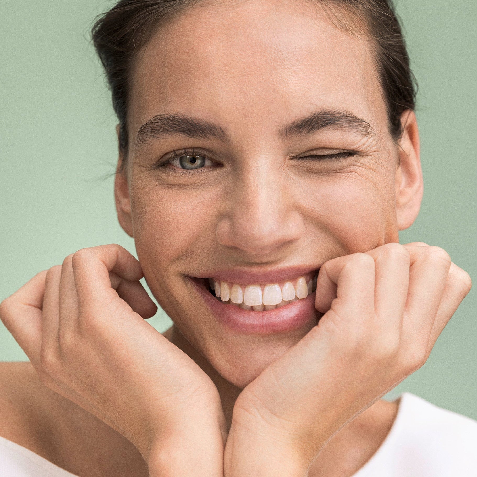 Frau hält den Kopf in den Händen und lächelt