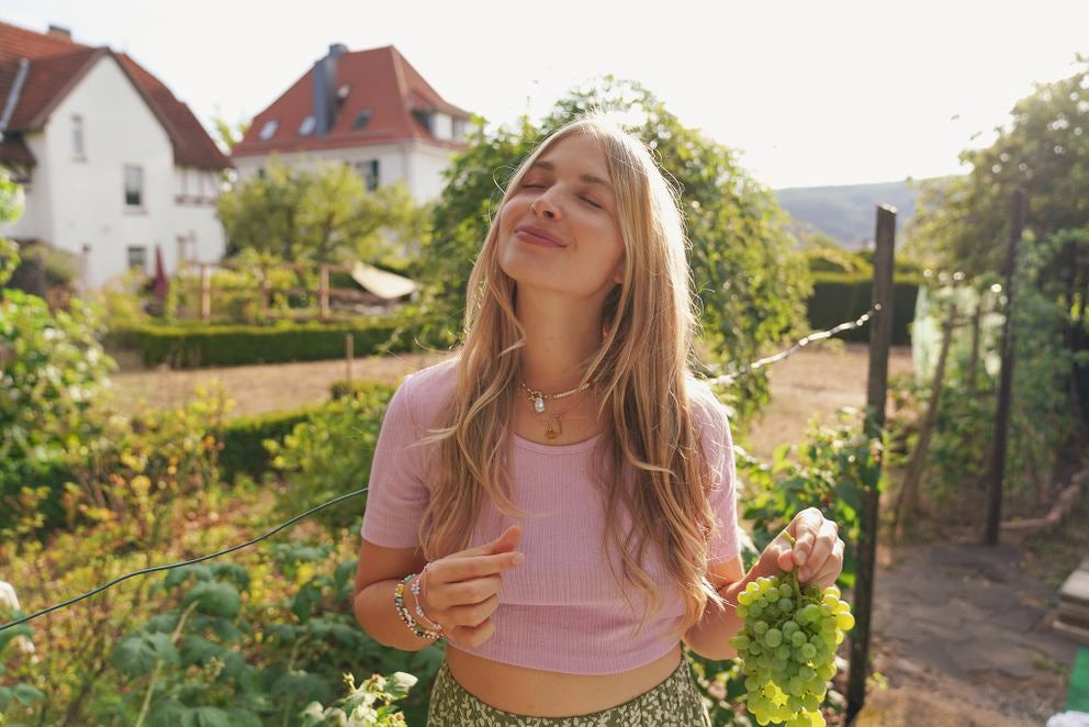 Frau im Weinberg hält grüne Weintrauben in der Hand