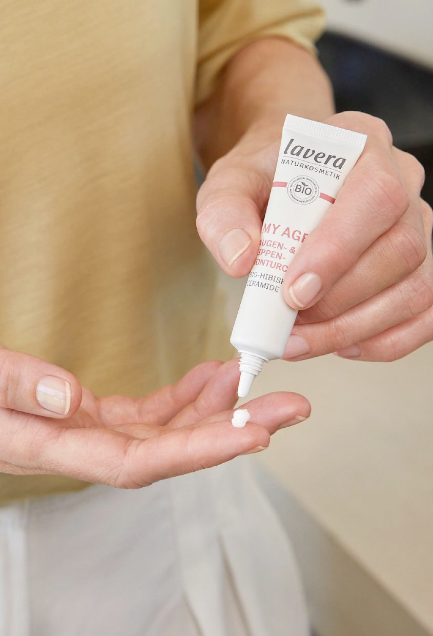 Hand drückt lavera MY AGE Augen- & Lippenkonturcreme auf Finger, Nahaufnahme