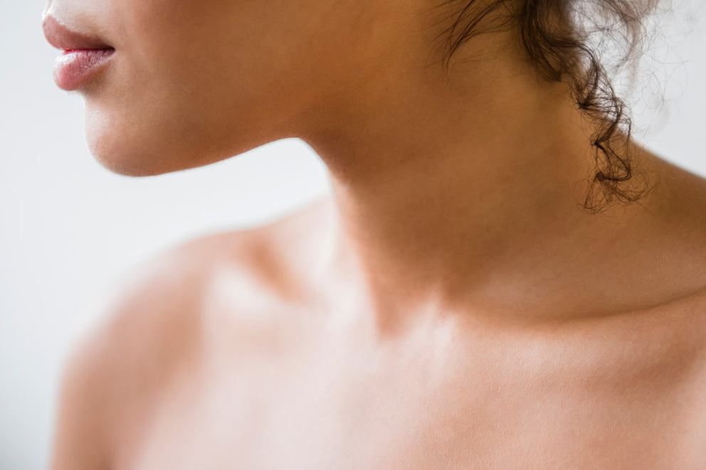 Nahaufnahme von Hals und Dekolleté einer Frau in Profilansicht