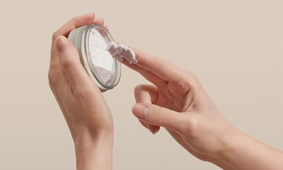 Deo-Creme wird mit dem Finger aus Tiegel entnommen