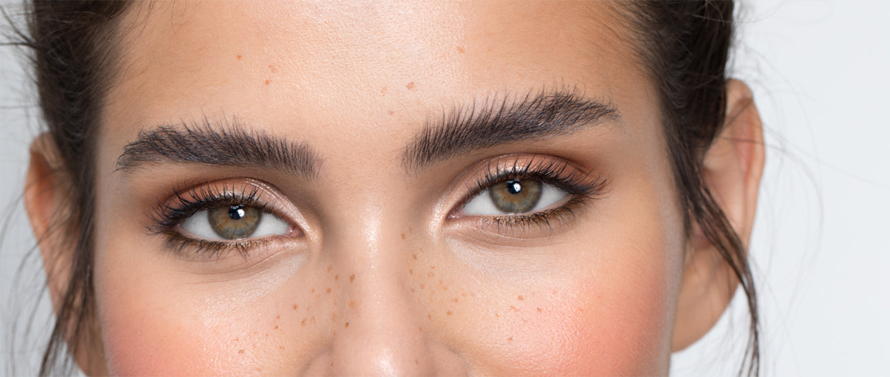 Nahaufnahme einer jungen dunkelhaarigen Frau mit hellbraunen Augen und gestylten dunklen Augenbrauen