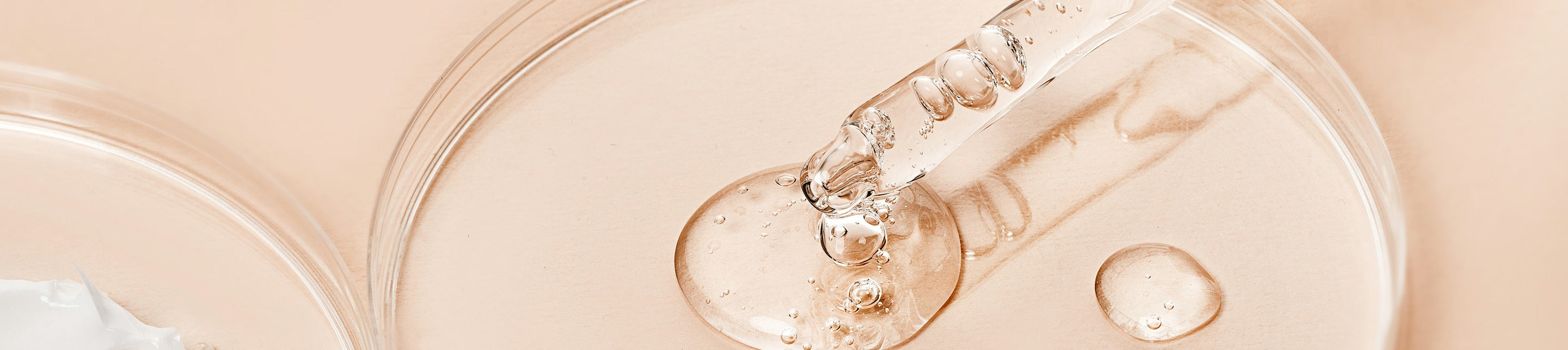 Pipette tropft klares Serum auf Glas, Makroaufnahme von Hautpflege-Textur