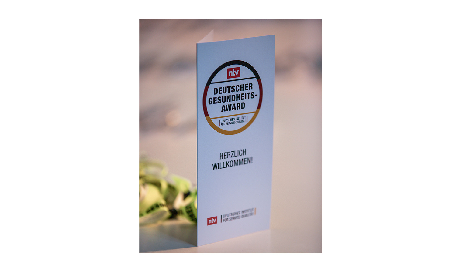 Deutscher Gesundheitsaward - Bildrechte: DISQ/ntv, Fotograf: Eric Harder ausgeklappter willkommens flyer deutscher gesundheitsaward 2022 auf tisch