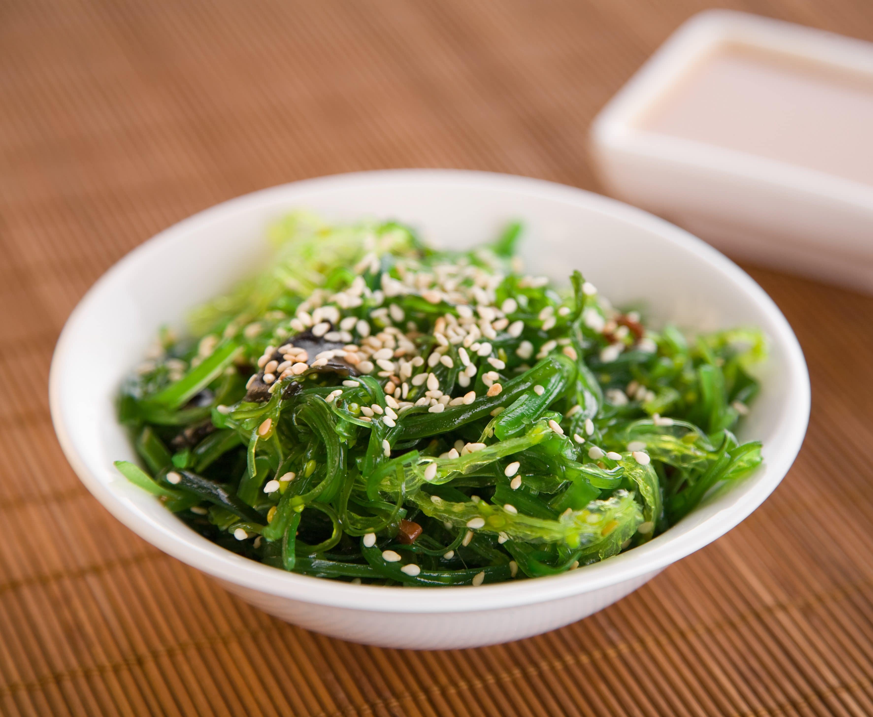 wakame-algensalat-in-weißer-Schale-stock-magazin-rezepte gruener wakame algen salat mit sesamkoernern in weißer porzellanschale