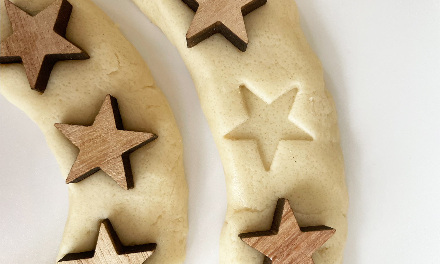 lavera-Adventsspirale-Praegung-Stern-Magazin-DIY nahaufname einer salzteigspirale mit holzsternen und einer prägung in sternenform auf weißem Untergrund